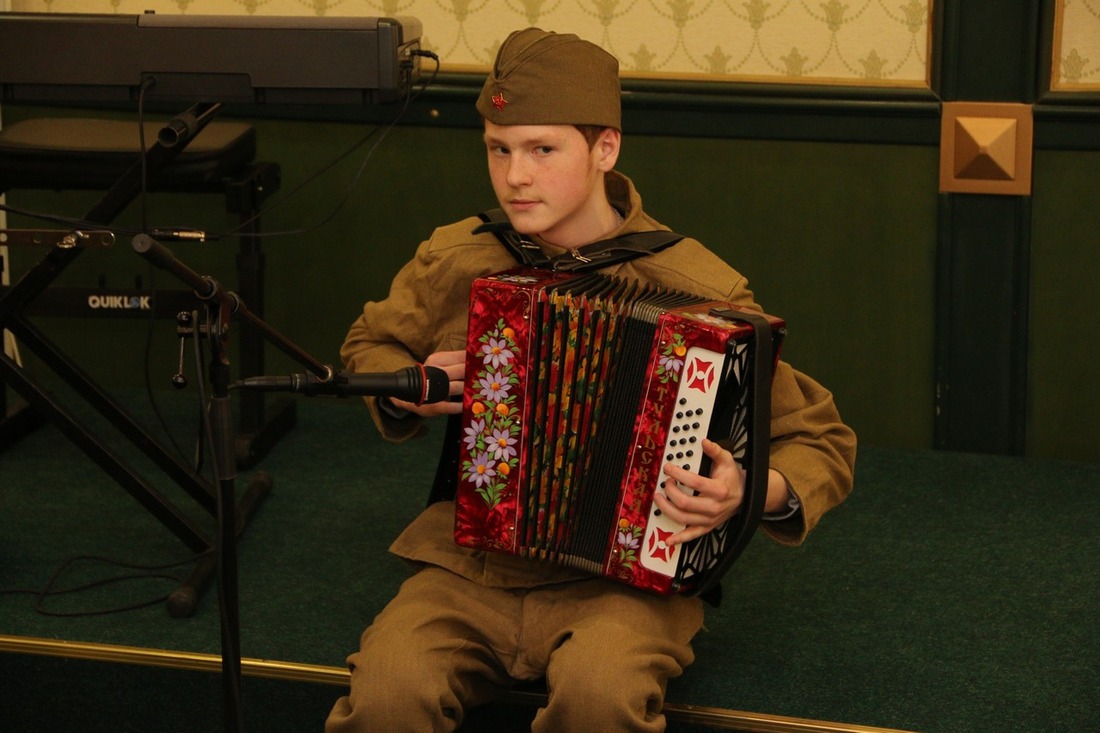 Молодой гармонист исполняет для ветеранов «Катюшу»