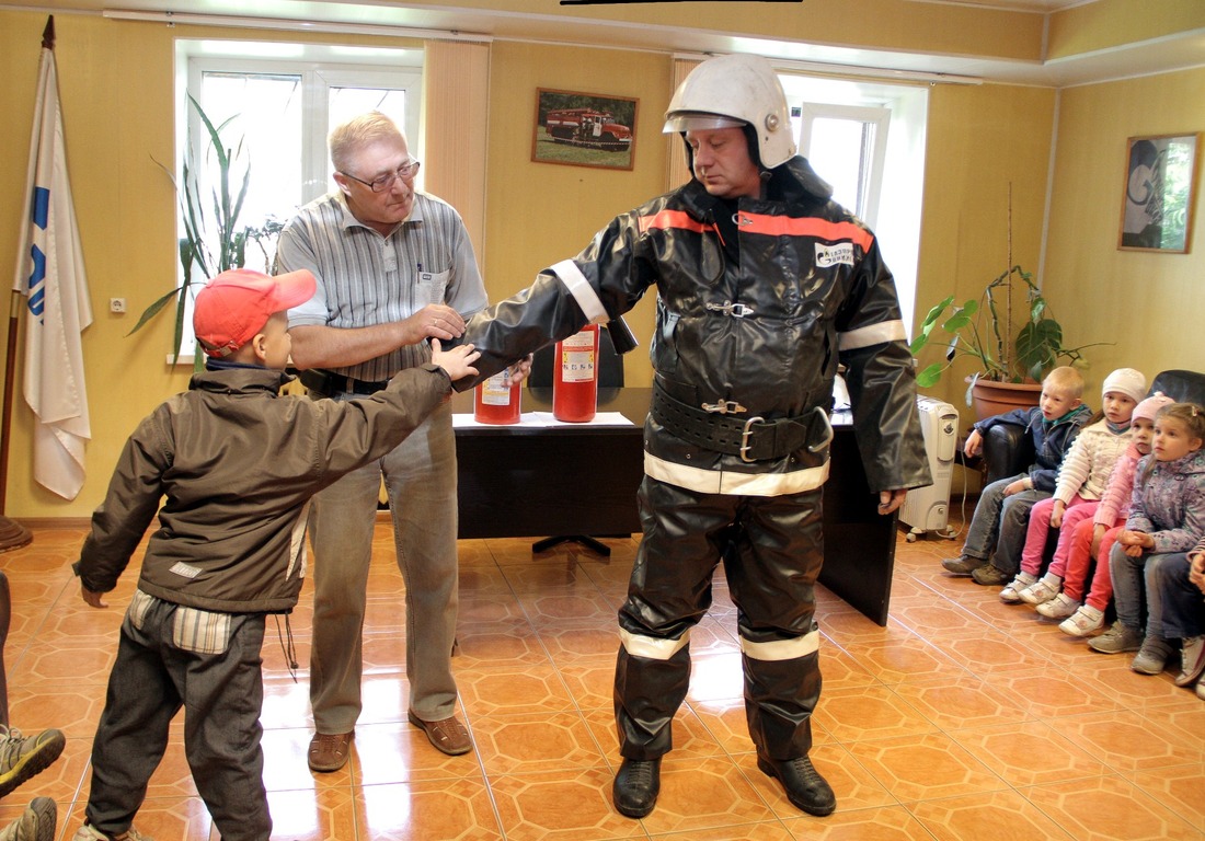 Командир отделения Юрий Улитин и инженер Виктор Вдовиченко рассказывают ребятам о защитных свойствах формы пожарного