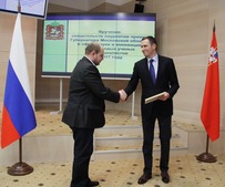 Заместитель председателя правительства Московской области — министр инвестиций и инноваций Подмосковья Денис Буцаев вручает награду Николаю Хохлачеву